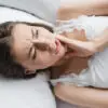 woman suffering from tooth pain while lying in bed