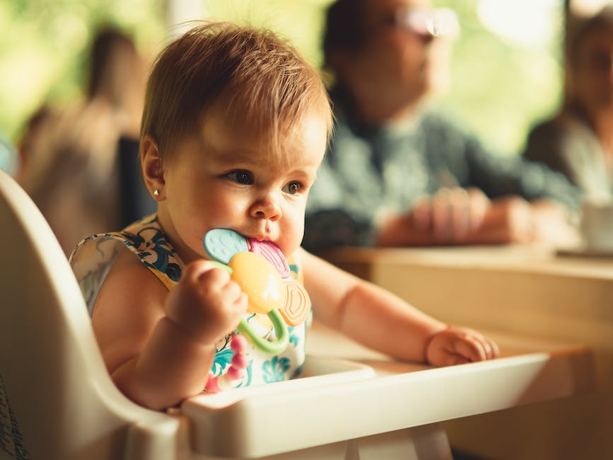 A close-up photo of a teething baby holding a teether in their mouth, with a relieved expression.