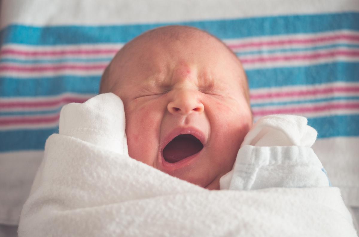 Image of a baby with teething symptoms, such as drooling and pulling ears